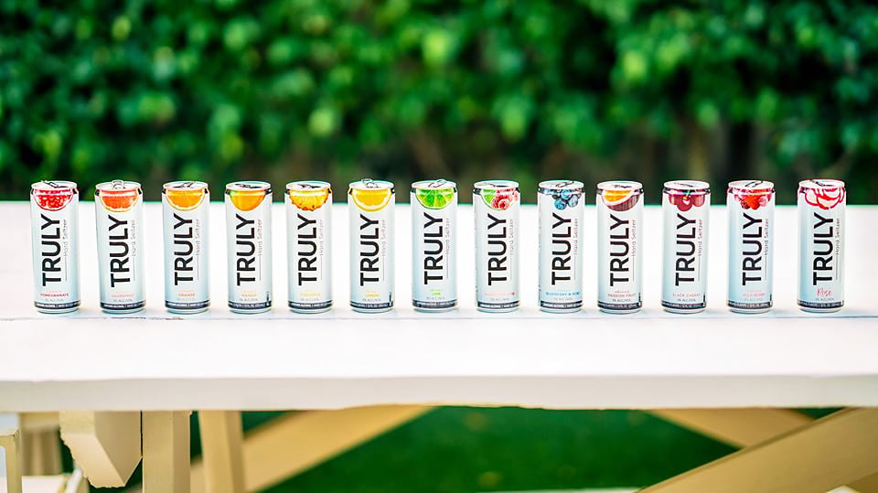 truly hard seltzer cans on table in front of shrubbery