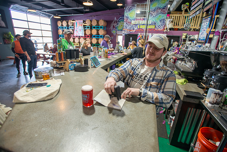 Bartender Ryse Caratini stamps an Ale Trail passport after serving a Blackberry Cream Ale at Fossil Cove Brewing Co. in Fayetteville