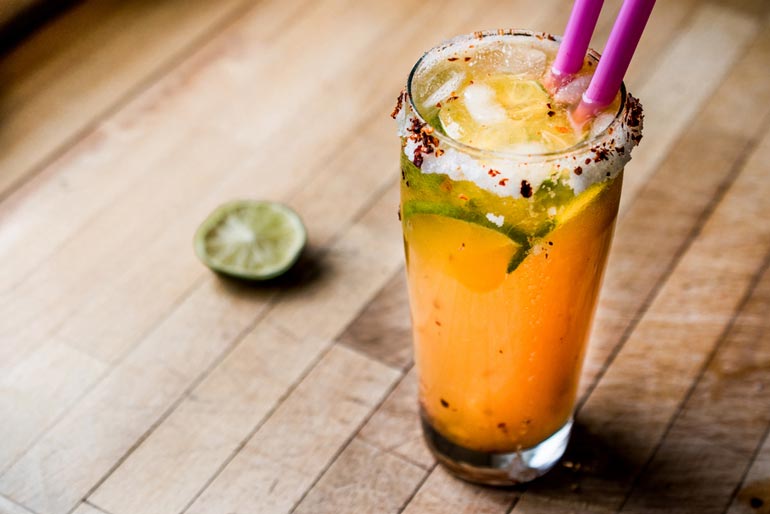 beer cocktail with pink straws and beer salt and chili pepper on rim