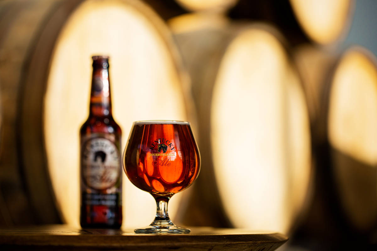 kentucky bourbon barrel ale bottle and glass atop a table in front of barrels