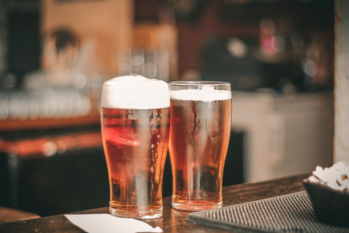 two foamy beers sitting atop a bar