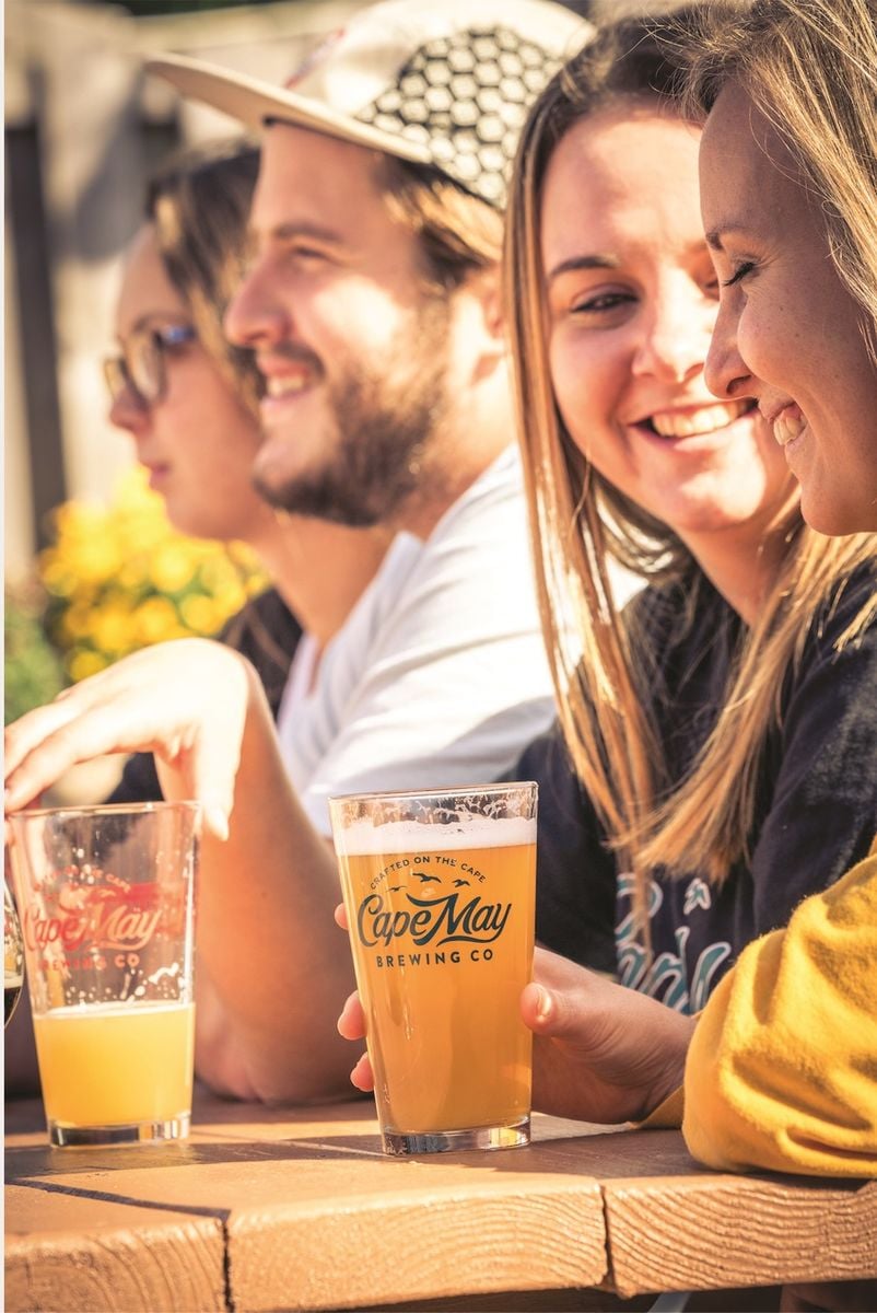 people conversing happily with cape may brewing co. beer glasses